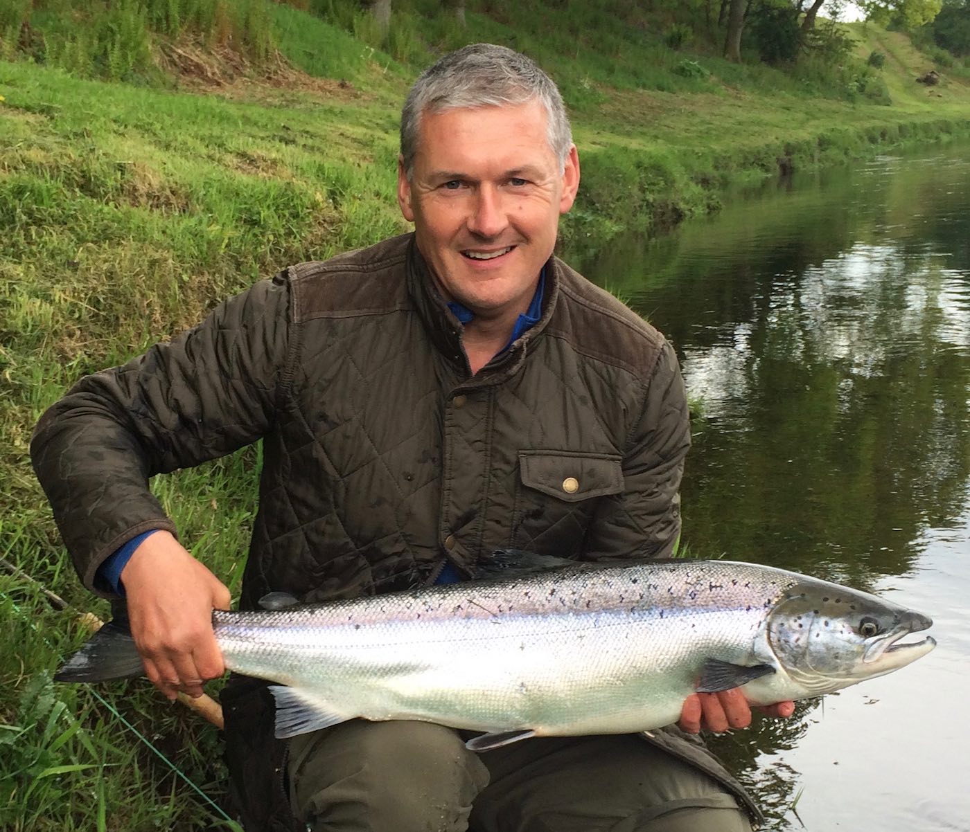 Jock Monteith is a well known professional salmon fishing tour organiser in Scotland and leading professional salmon fishing guide. Jock is holding a perfect fresh run 14lbs Summer salmon in this shot at the Daffodil Lie Pool of the River Tay's Kinnaird Beat which he hooked after a few casts while testing out a salmon fishing trip client's new fly rod .