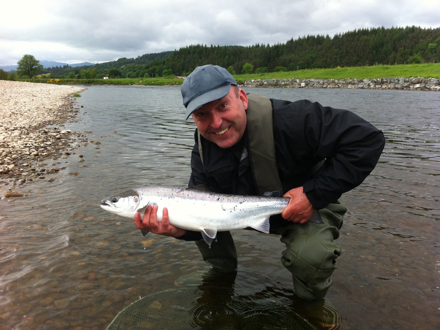 This was 1 or 4 perfect salmon that were caught by this new salmon fisher on the River Tay where he came to learn how to salmon fish. This one was caught at the Guay Pool near the Perthshire town of Dunkeld which is a very popular Tay Valley fishing area for salmon fishing holiday guests. Look at the perfect silvery flanks of this fine fish and note this happy salmon fisher is wearing a life jacket for wading safety.
