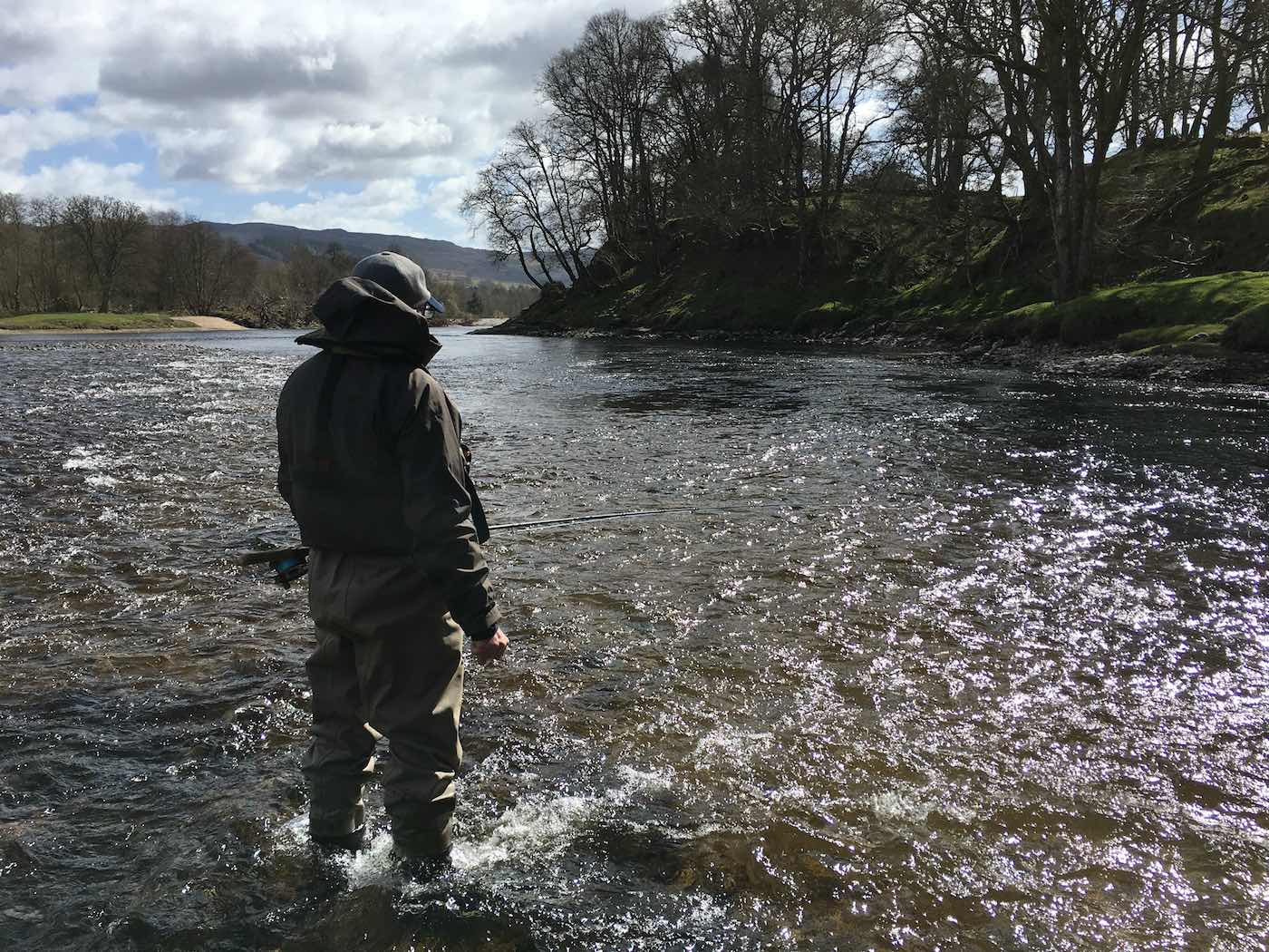 This salmon fishing trip angler is wading down through the shallow water bar in the centre of the River Tay at the neck of the Rock Pool on the Kinnaird salmon beat near Dunkeld. This salmon fisher was taught to wade with stealth by his salmon fishing instructor which is an important salmon fishing skill to master.