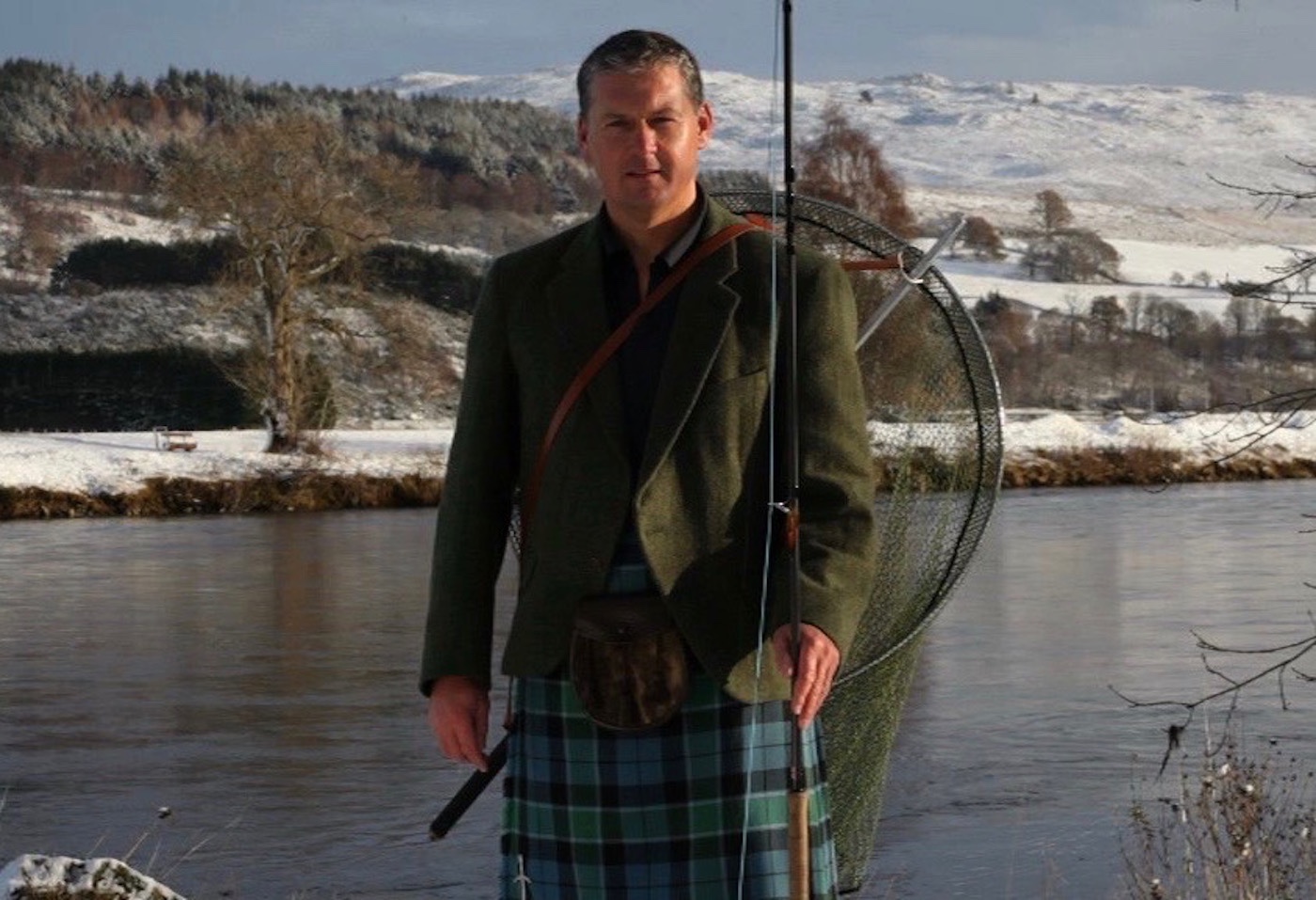 This photograph of professional Scottish salmon fishing guide Jock Monteith was captured by TV producer Chris Webster outside Ferry Cottage on the Kinnaird Estate of the River Tay in Perthshire. You can see the snow clad hills and riverbanks in the background.