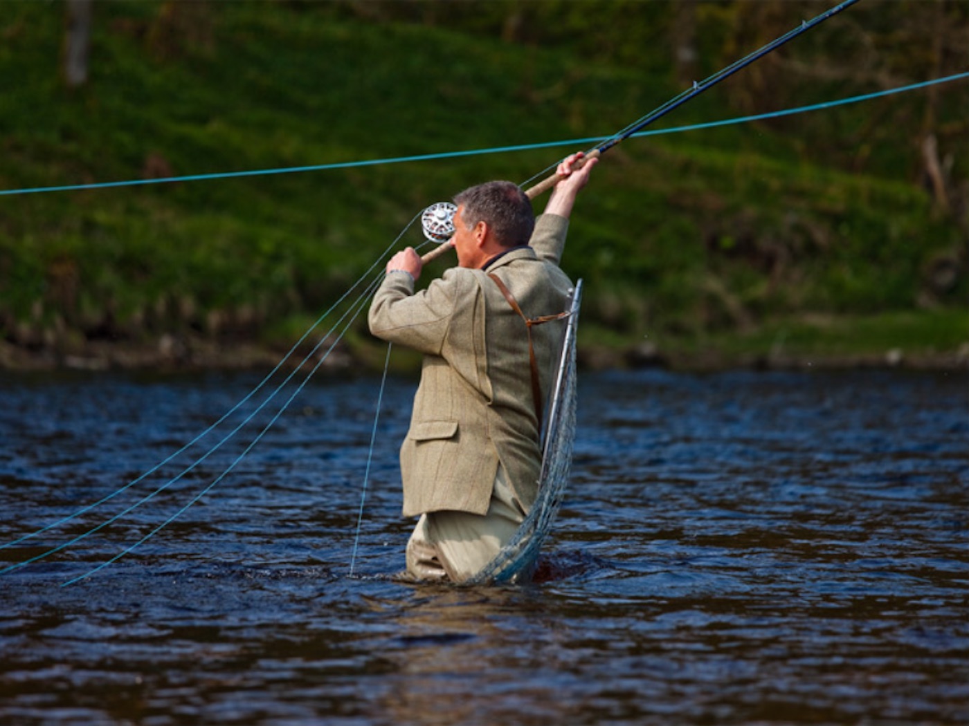 Here's professional Scottish salmon guide Jock Monteith our delivering a long fly fishing line across the River Tay near Dunkeld wearing a traditional heavyweight Tweed jacket that hand been handmade by Haggarts of Aberfeldy.