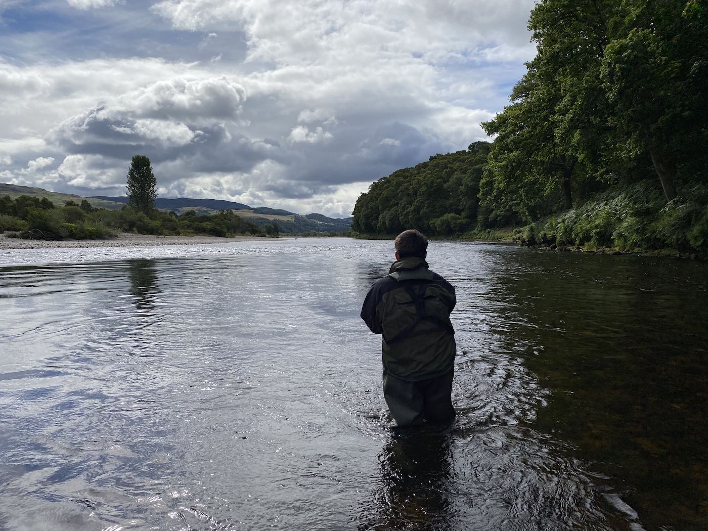 Here's a guided salmon fishing guest fishing down through the right hand bank of the River Tay near Dunkeld. This area of the river is close to the towns of Pitlochry & Dunkeld. The dark shadowy water where you see the reflection of the tree is an exceptionally good salmon lie. The shadow being cast by the tree on the opposite riverbank is a great salmon lie that produces many salmon for our guided fishing guests each year.