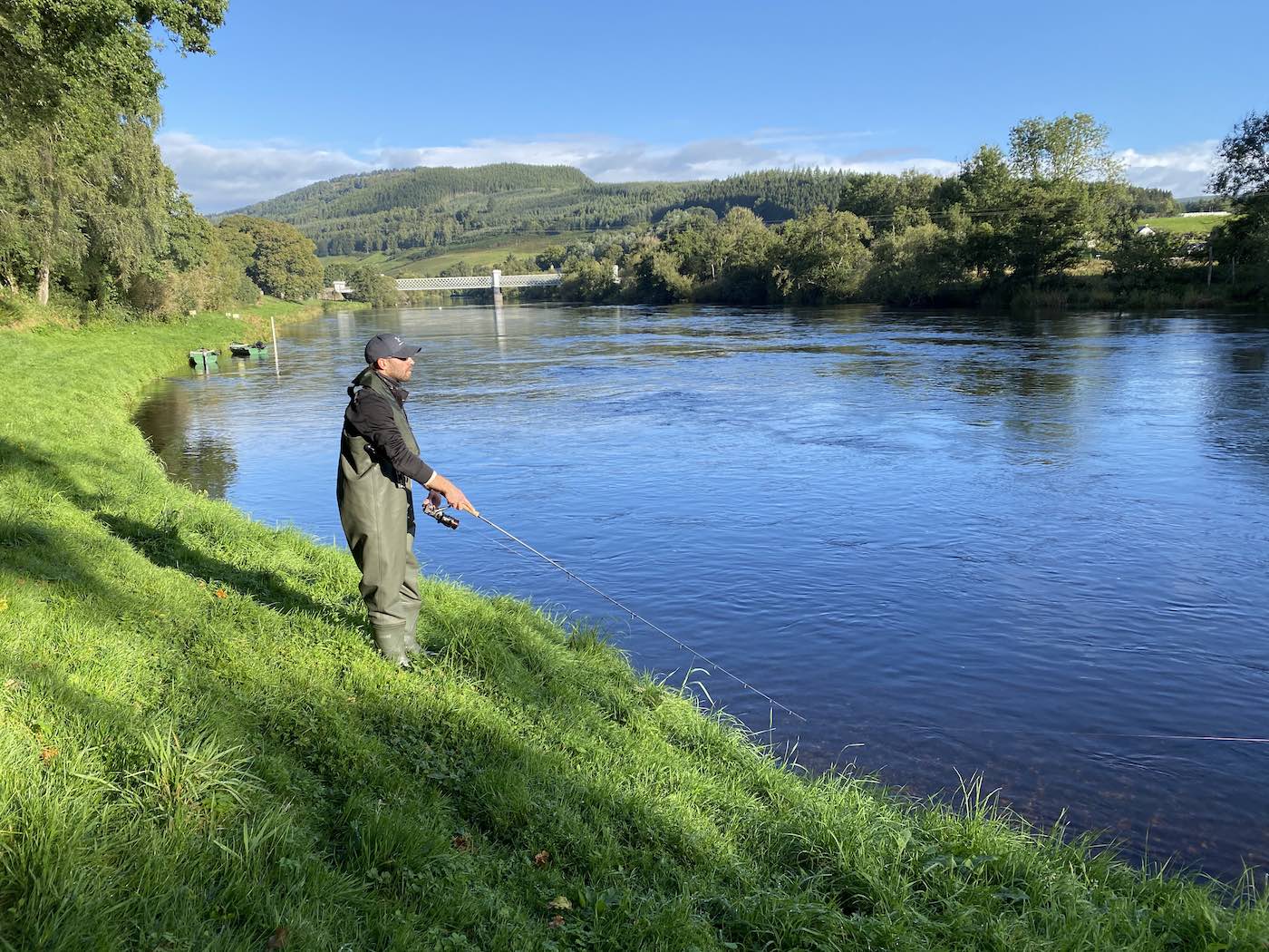 How can clearly see the perfect iron Logierait Bridge behind this River Tay spin fishing guest. This area of the Tay near Pitlochry has some lovely deep holding water for salmon which can be perfectly targeted with a spinning rod & spinner. Look at the lovely green grassy riverbank which makes it easy for fishing guests to fish from.