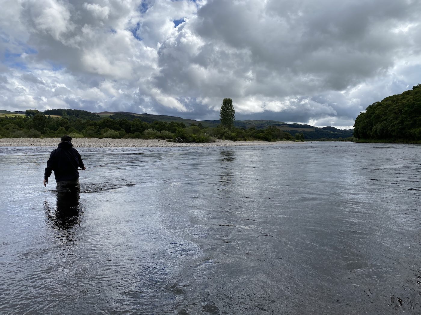 Knowing how and where to wade through a salmon pool like this fisher is doing for minimal disruption is a vital skill to master in Scottish salmon fishing. Most anglers think that wading deeper is better but the true facts about wading are quite the opposite. Observe that this salmon fisher is only at knee depth so as not disturb the salmon pool which is essential for salmon fishing success. 