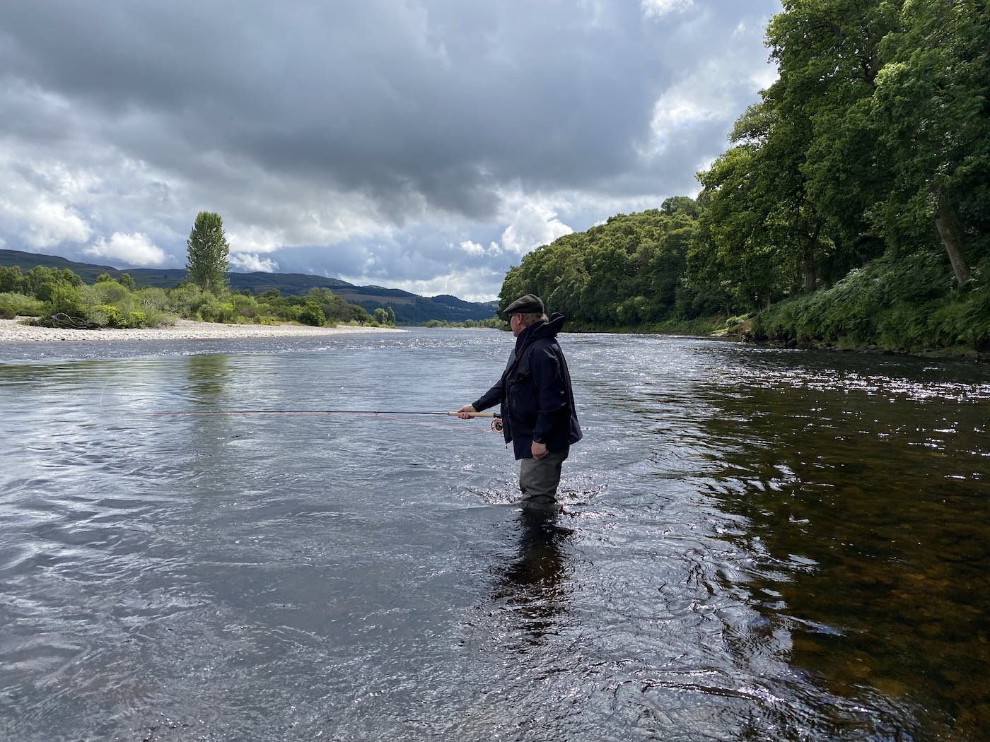 Learning to fish for salmon on Scotland's largest and most famous salmon river is a real natural thrill under the supervision of a professional salmon guide. This picture was taken on the River Tay near Logierait with a guided salmon fisher out presenting his salmon fly through a well know salmon fishing hot spot during July.